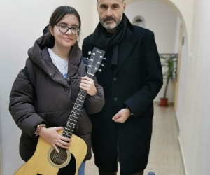 O chitară, un om generos și o fetiță fericită